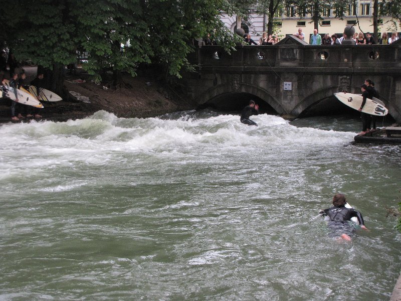 Eisbach_englischer garten_surfen.jpg - Bij het Haus der kunst stroomt de Eisbach zo hard uit een tunnel dat je er echt kunt surfen. Steeds gaat één surfer het water op en zodra hij valt is de volgende aan de beurt.